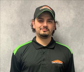 Male employee in a black logo SERVPRO jacket, posing