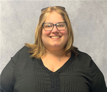 Female, black outfit smiling and wearing glasses