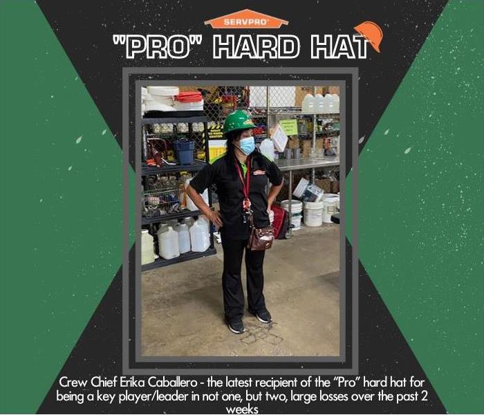 female employee posing in a warehouse wearing a hard hat